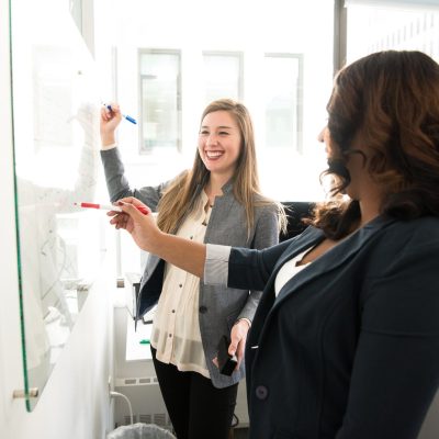 Two Women in Front of Dry-erase Board